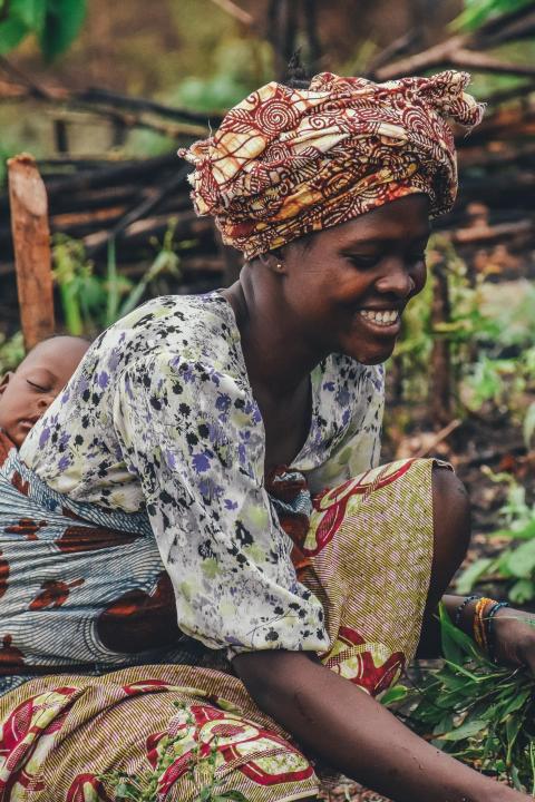 sustainable food systems - woman holding her baby while farming