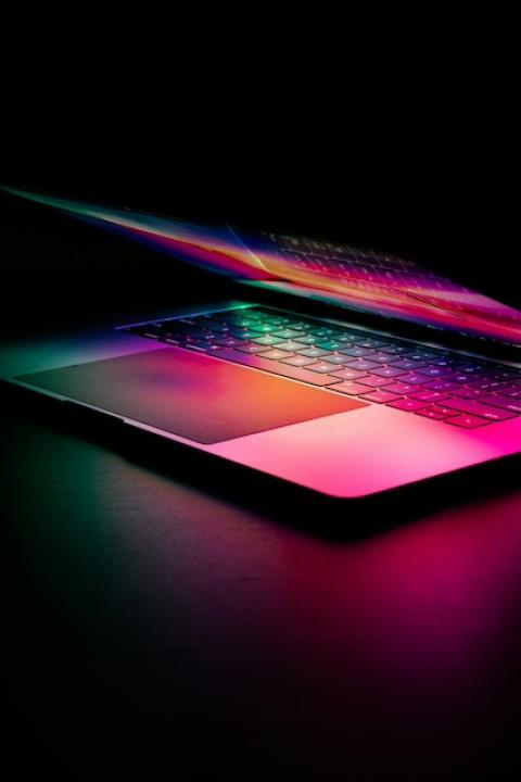 A laptop lit by multicolor light — artificial intelligence