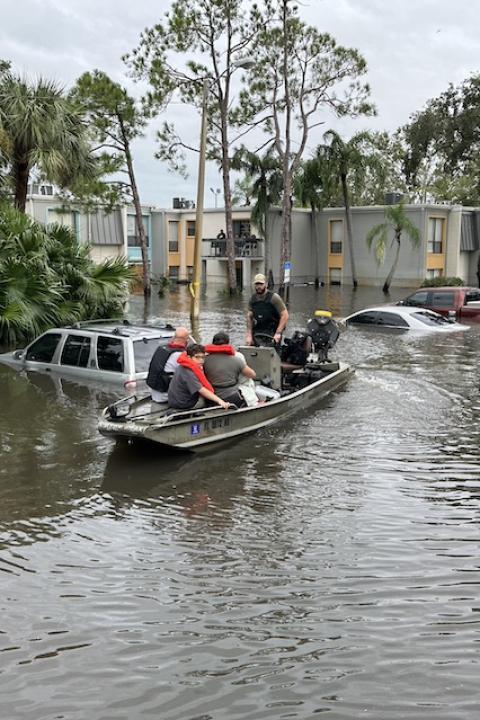 A Florida Fish and Wildlife Conservation Commission officer uses a boat to help people get out of a flooded area — climate resilience
