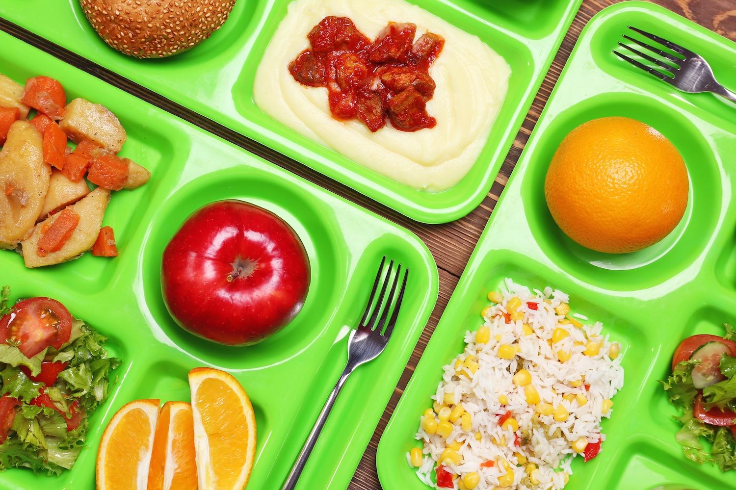 close-up of school lunch trays with food — school systems adopt reuse for serving trays and cutlery