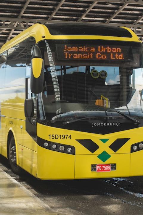 A yellow bus that's a part of the Jamaica Urban Transit Company fleet — CNG buses