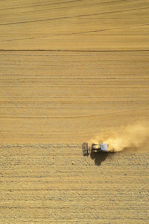 An aerial view of two tractors harvesting a field — cover crops