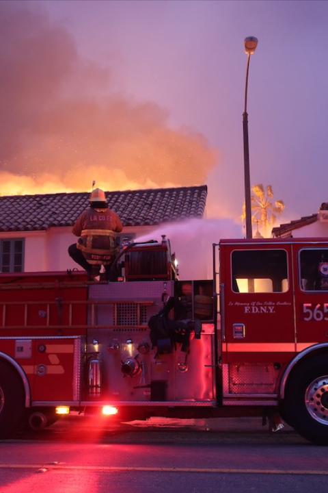 A firefighter sprays water onto a fire from the top of a firetruck — evacuation