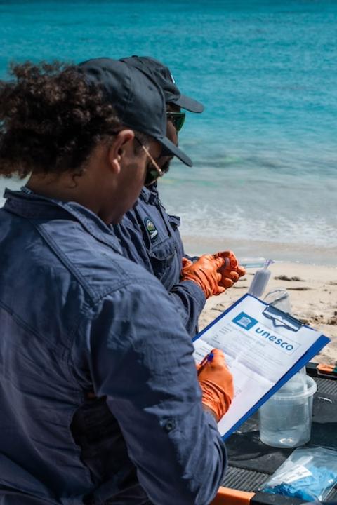 Researchers hold eDNA samples and take notes on a clipboard along along Australia's Ningaloo Coast.