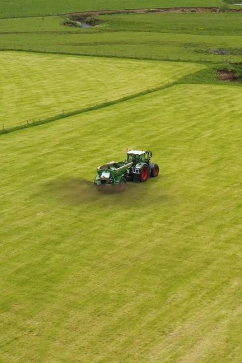 An aerial view of a tractor spreading crushed basalt rock on a farm field — enhanced rock weathering