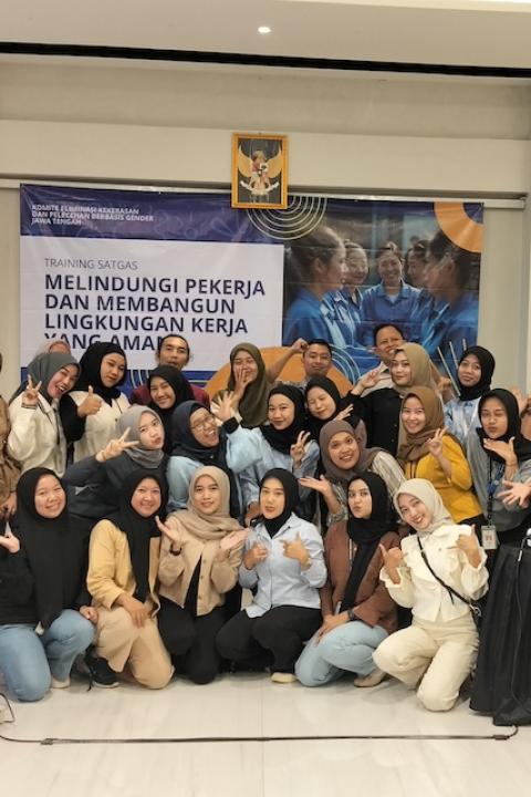 Garment factory workers and union members smile at the camera for a group photo at a training session — gender justice agreement