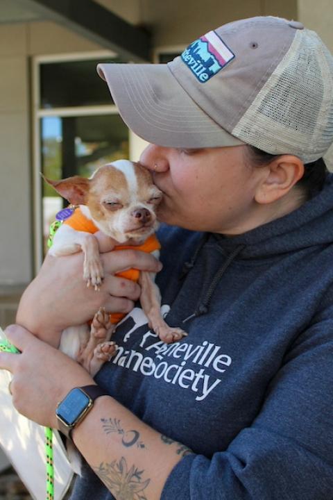 A member of the Asheville Humane Society kissing a small dog on the head during Hurricane Helene recovery efforts.
