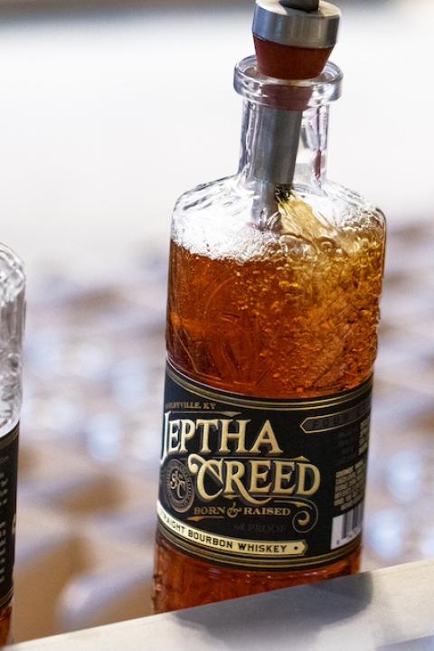 Bottles of Jeptha Creed bourbon being filled in an assembly line.