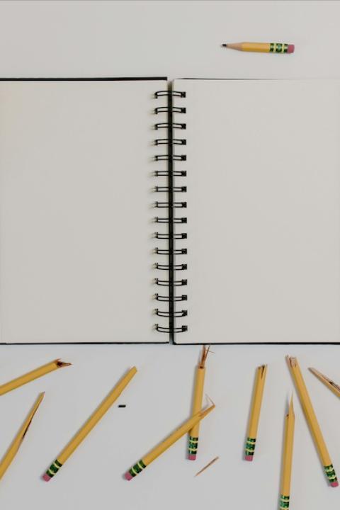 A notebook surrounded by broken pencils — failure.