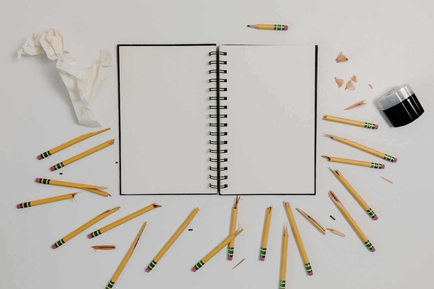 A notebook surrounded by broken pencils — failure.