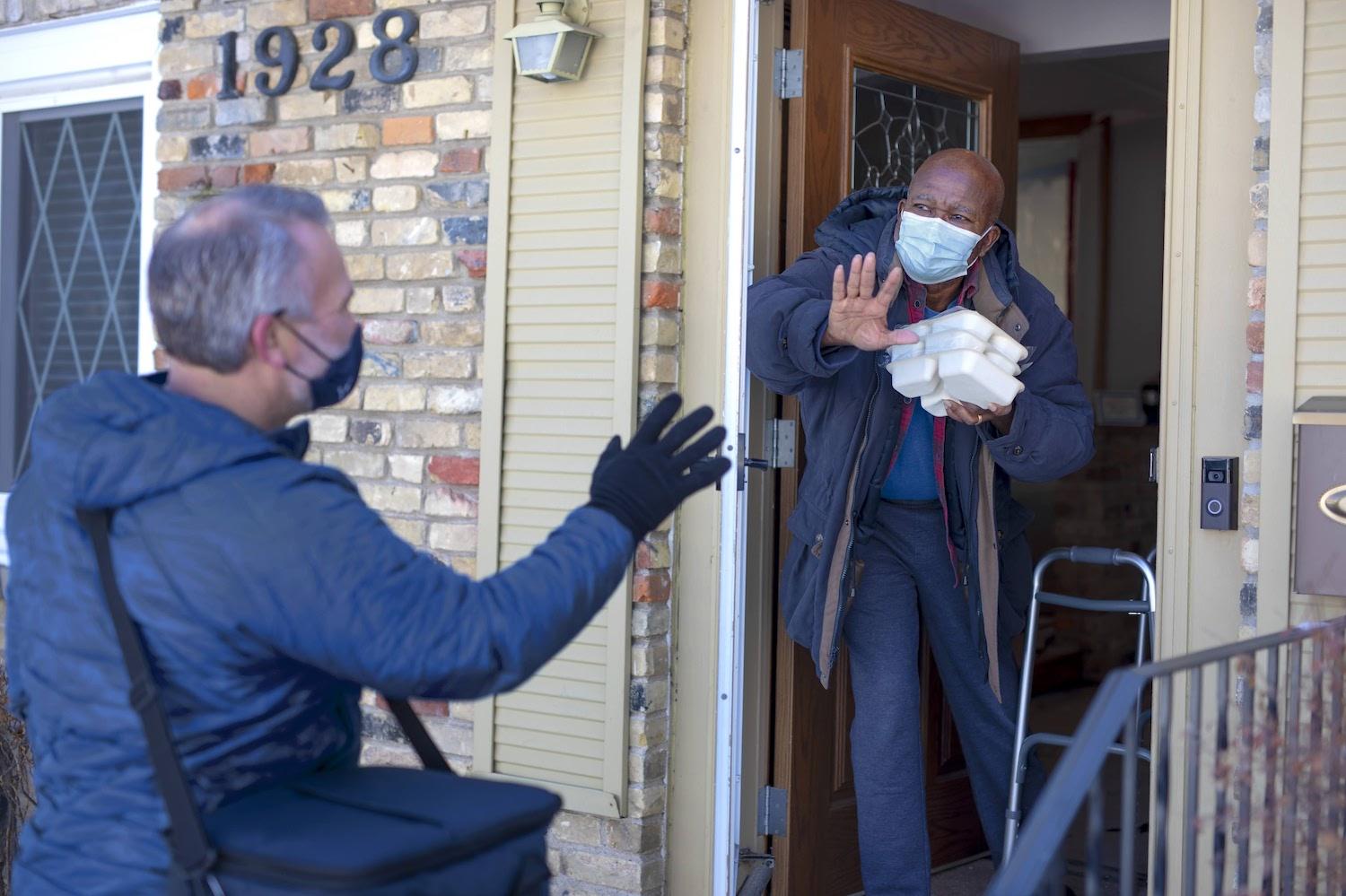 Meals on Wheels volunteer delivers food to a senior at his home