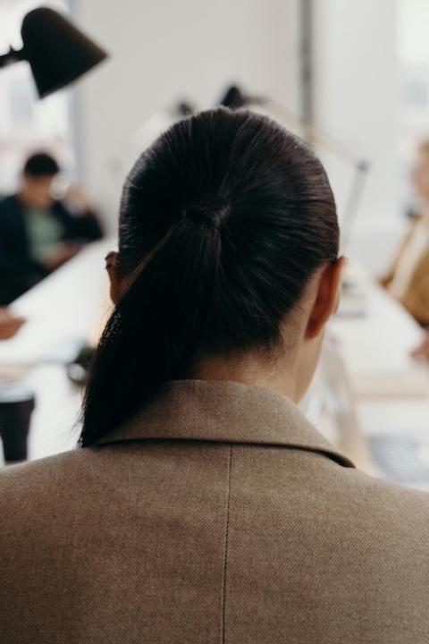 A woman sits at a table during a meeting with her back to the camera — menopause support