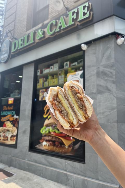 Person holding Plantega plant-based sandwich in front of corner store