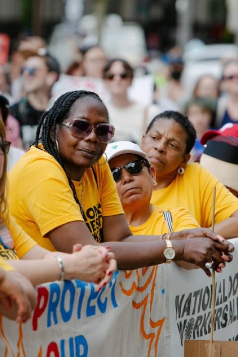 National Domestic Workers Alliance members wearing yellow alliance t-shirts stand together at a rally — POWER Act