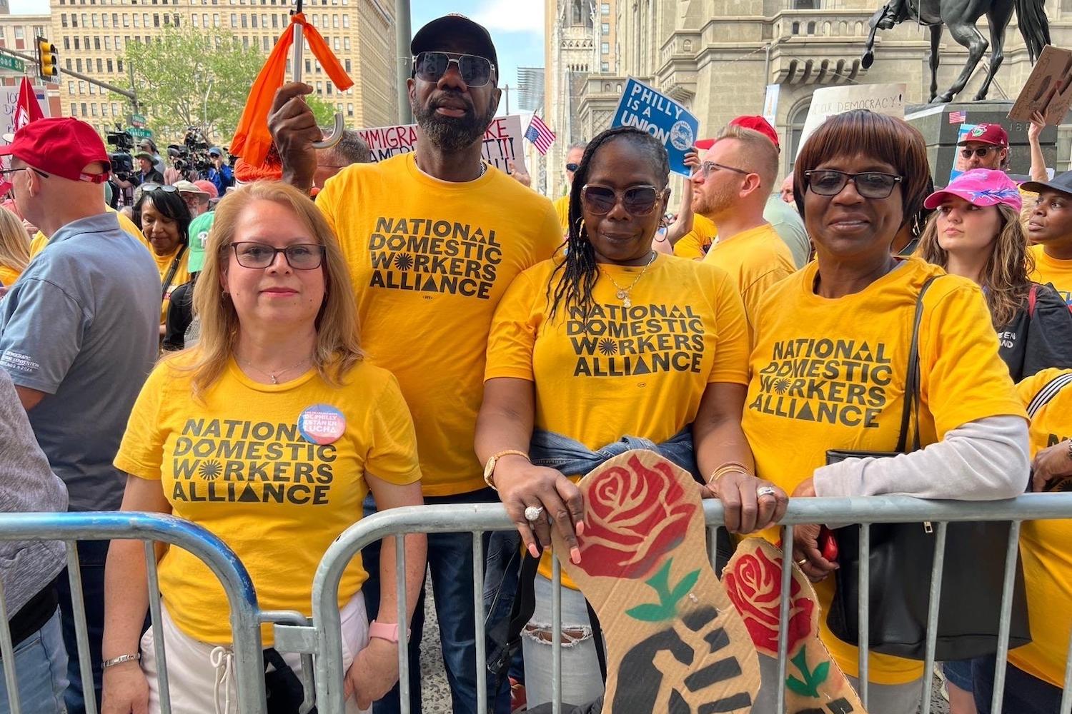 National Domestic Workers Alliance members wearing yellow alliance t-shirts stand together at a rally — POWER Act