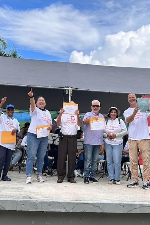 The Interstate Renewable Energy Council Puerto Rico team and residents of Castañer stand together celebrating — grid resilience