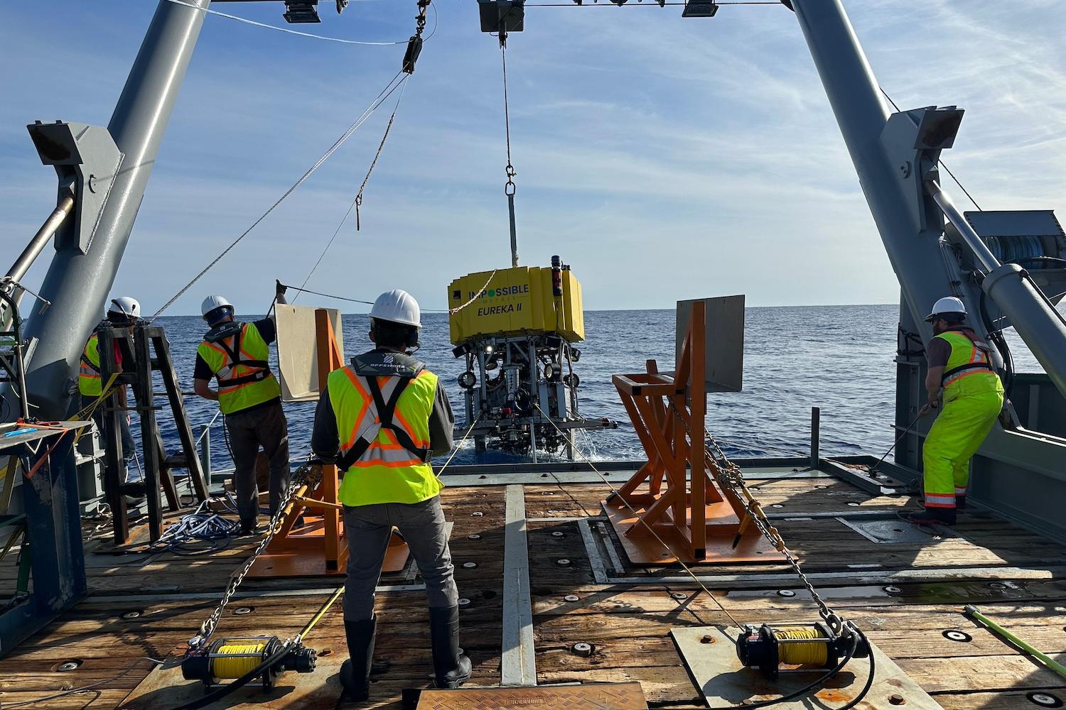 The Impossible Metals team lowers an autonomous vehicle for deep-sea mining into the water for a test with a pulley system.