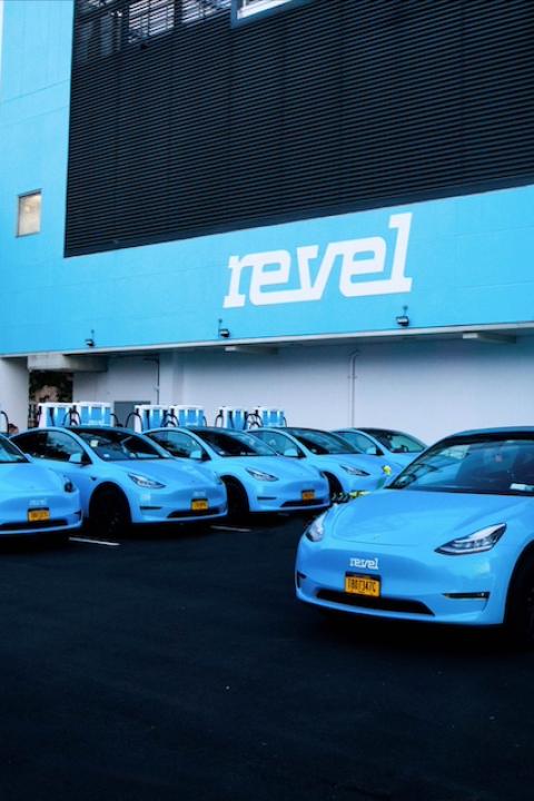 A fleet of Revel EVs lined up at a charging station.