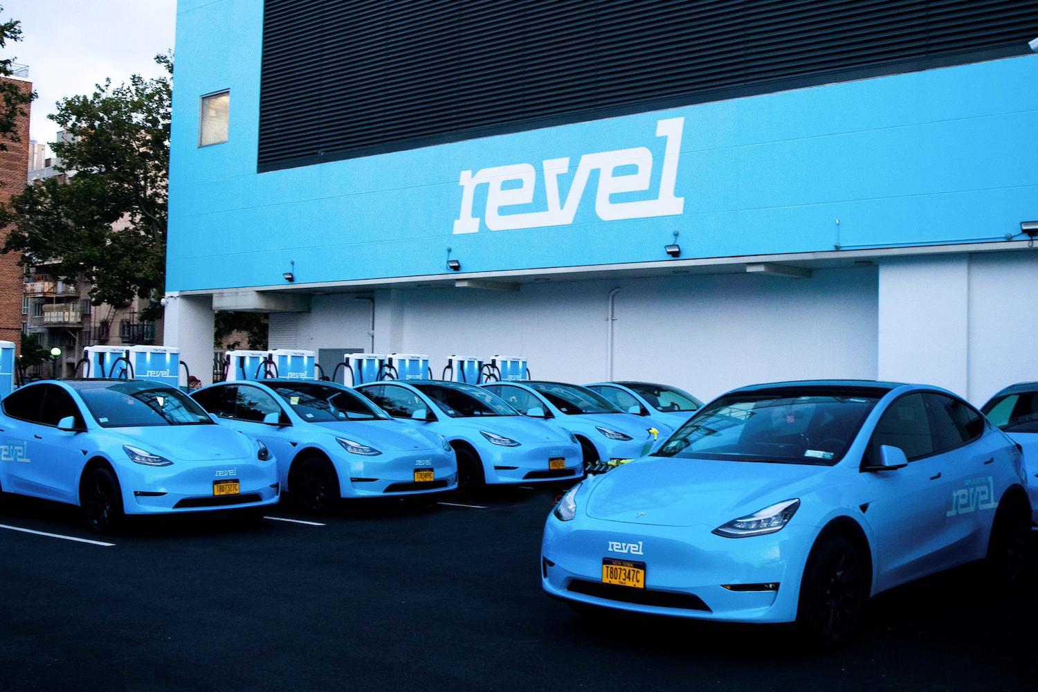A fleet of Revel EVs lined up at a charging station.