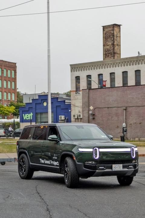 A green Rivian R1 pulling a Billion Oyster Project boat — The Good Project