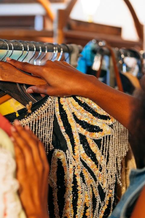 A person looking though a rack of secondhand clothing — tariffs 