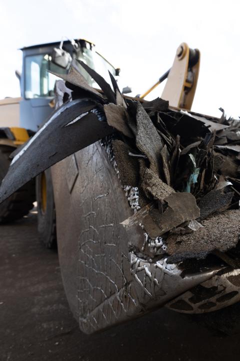 single recycling - backhoe carrying shingle waste for recycling