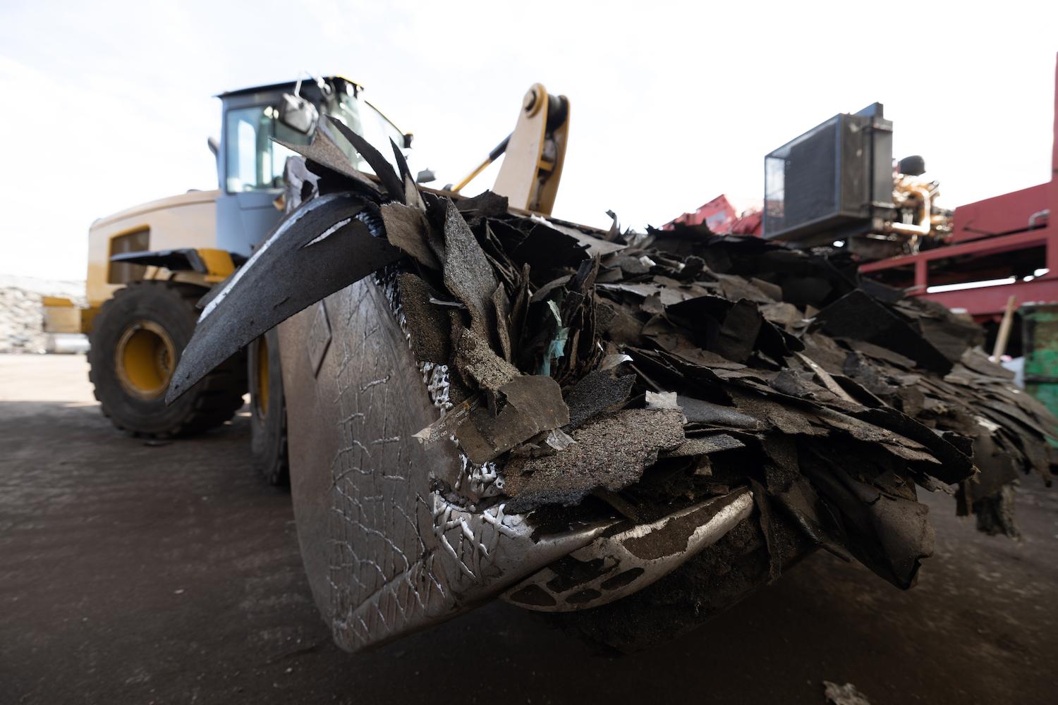 single recycling - backhoe carrying shingle waste for recycling