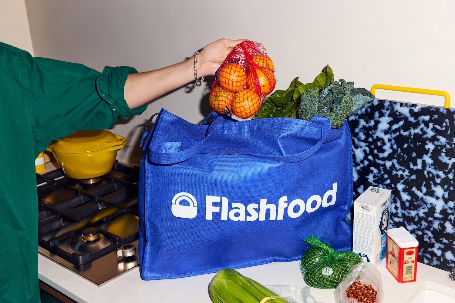 A person pulls a bag of oranges out of a reusable Flashfood bag — solutions journalism