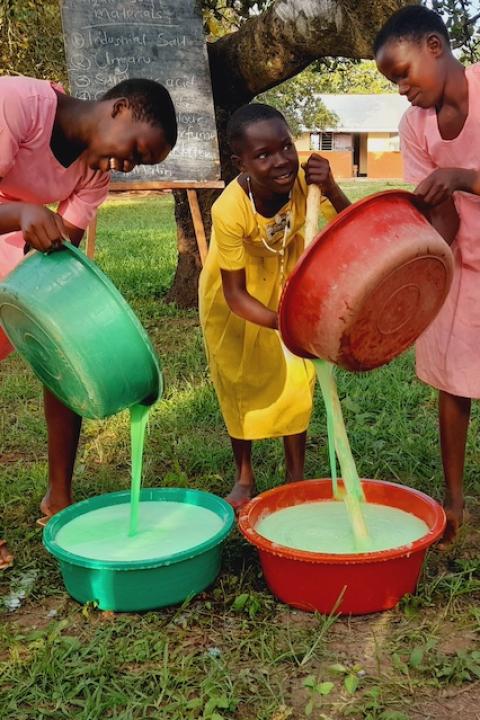 Three girls mix soap in buckets are a part of a Surge for Water soapmaking lesson.
