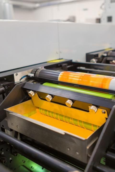 A flexographic printing machine rolling yellow ink onto packaging material — VOC