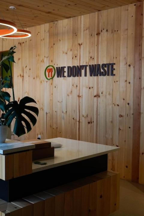 The We Don't Waste logo on a wall at its new facility — food waste 