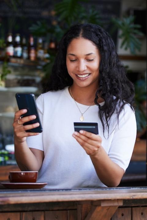 woman using a credit card and phone for online banking — financial equity — closing the racial wealth gap
