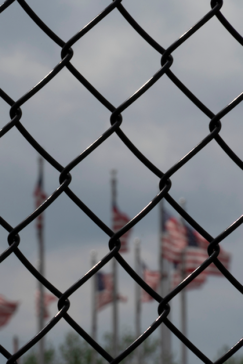 Waving American flags behind fence grid — prisons and prison risk in the US